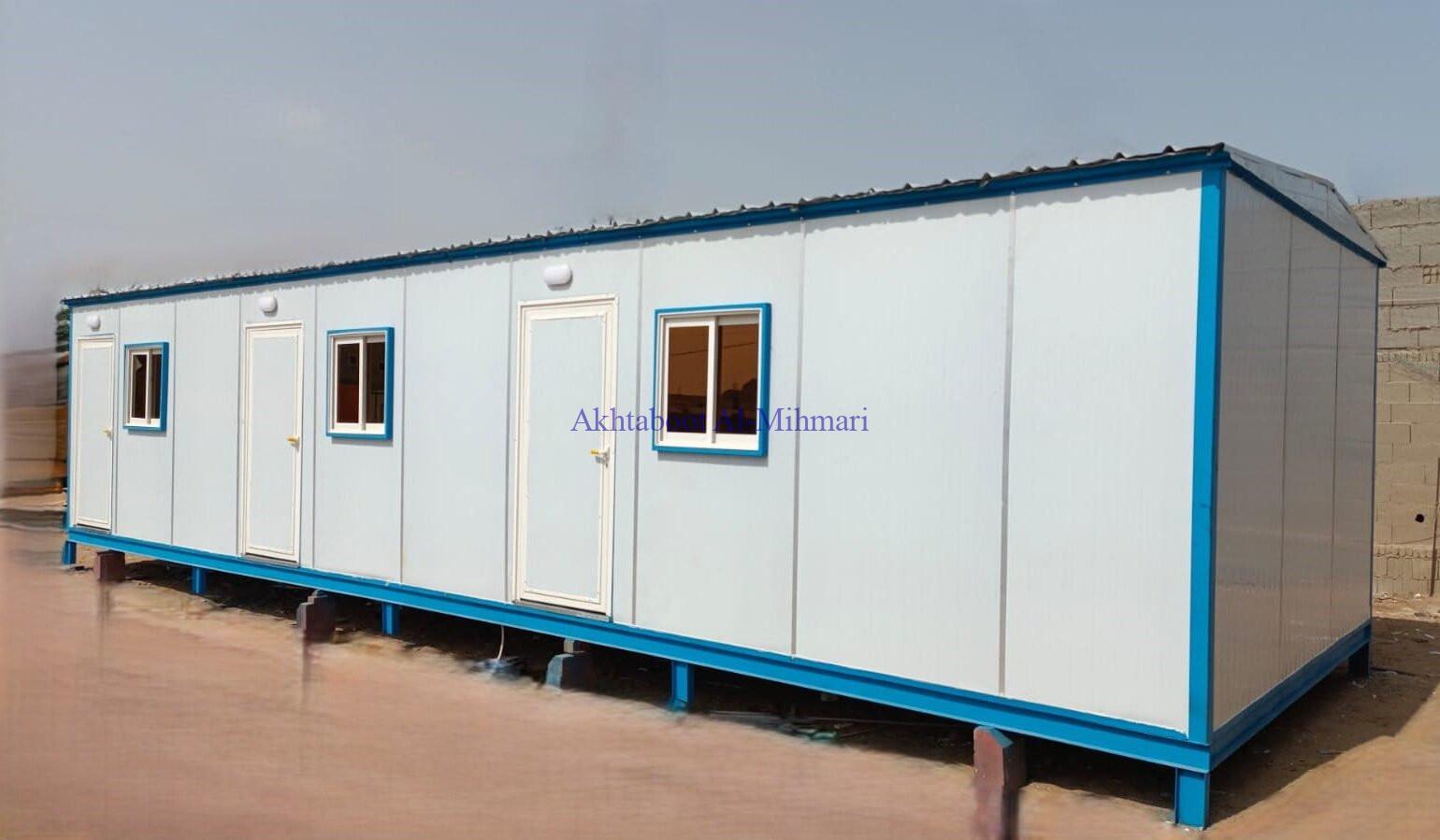 Image of a modular cabins being used as a construction site office: A prefabricated modular cabin with desks, chairs, and computers inside, serving as a temporary workspace for a construction project.